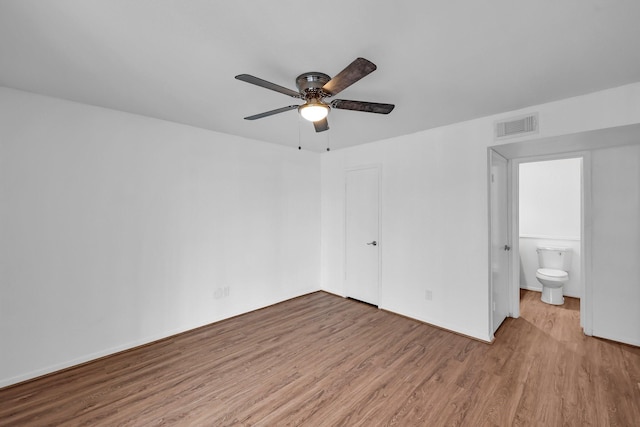 unfurnished bedroom featuring visible vents, ensuite bath, ceiling fan, wood finished floors, and a closet