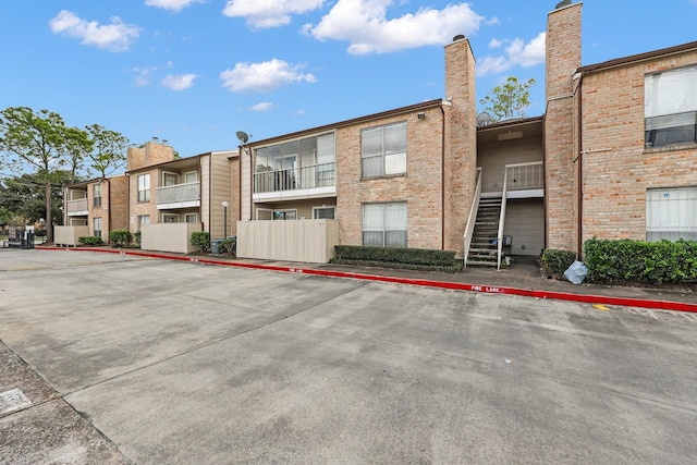 view of property featuring stairs and uncovered parking