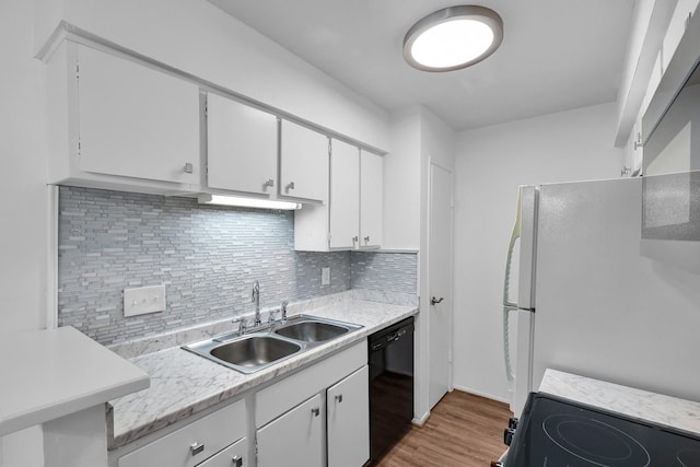 kitchen featuring tasteful backsplash, light countertops, white cabinetry, a sink, and black appliances