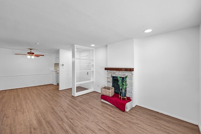 living area featuring a brick fireplace, baseboards, and wood finished floors