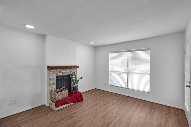 unfurnished living room featuring a brick fireplace, baseboards, wood finished floors, and recessed lighting