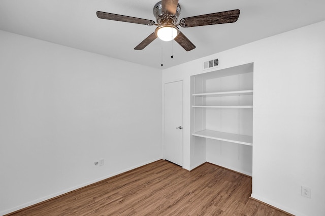 unfurnished bedroom featuring a closet, visible vents, baseboards, and wood finished floors