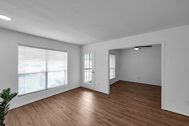 unfurnished room featuring a ceiling fan, baseboards, and wood finished floors