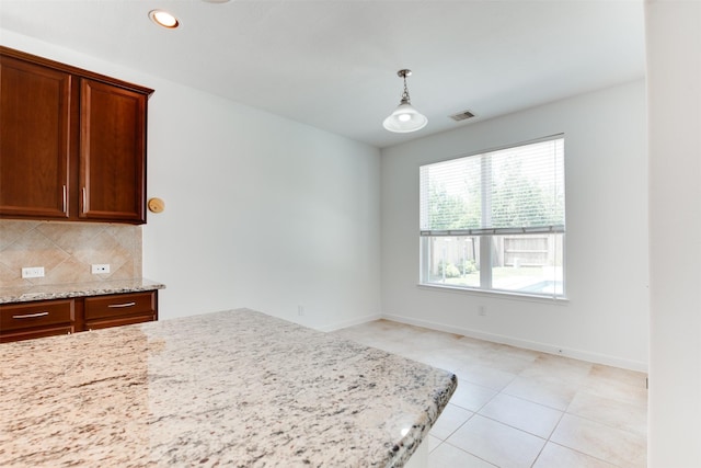 kitchen featuring light tile patterned floors, decorative backsplash, light stone counters, and decorative light fixtures