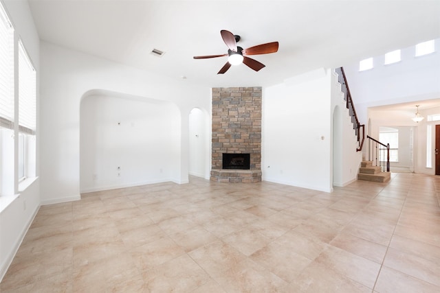 unfurnished living room with ceiling fan and a stone fireplace