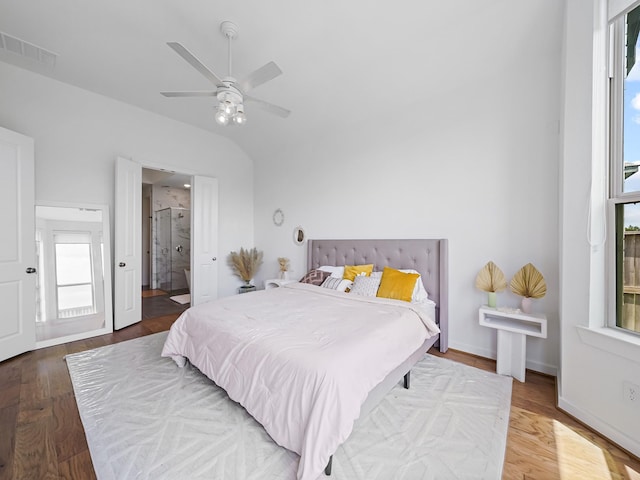 bedroom with hardwood / wood-style flooring, vaulted ceiling, ceiling fan, and ensuite bath