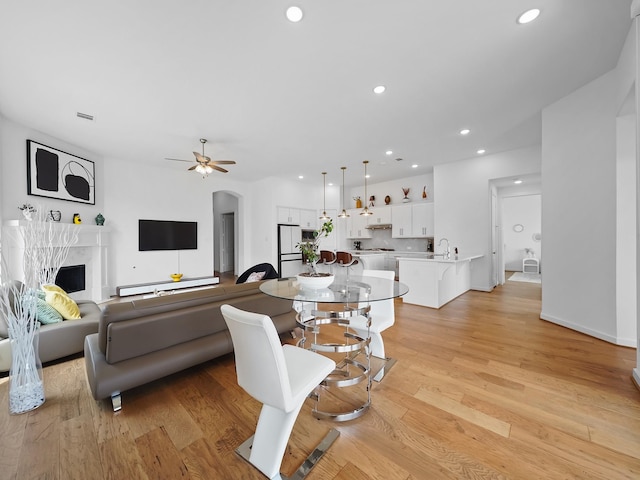 living room featuring sink, a high end fireplace, light hardwood / wood-style floors, and ceiling fan