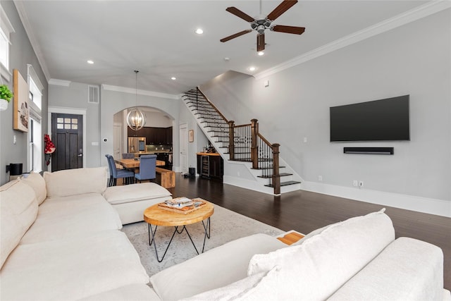 living room featuring dark hardwood / wood-style flooring, crown molding, and ceiling fan with notable chandelier