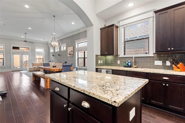 kitchen featuring sink, tasteful backsplash, ornamental molding, a kitchen island, and pendant lighting