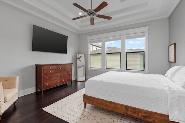 bedroom featuring dark hardwood / wood-style flooring, a tray ceiling, and ceiling fan