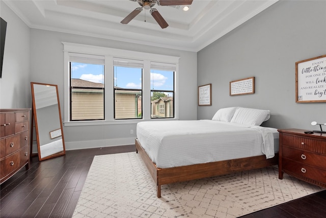 bedroom with dark wood-type flooring, ceiling fan, and a tray ceiling