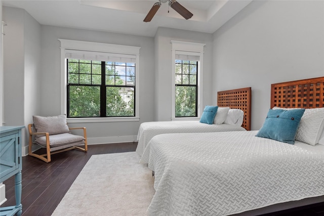 bedroom with ceiling fan, dark hardwood / wood-style floors, and a raised ceiling