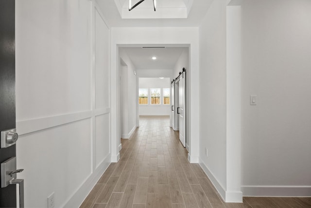 corridor featuring a barn door and light hardwood / wood-style flooring