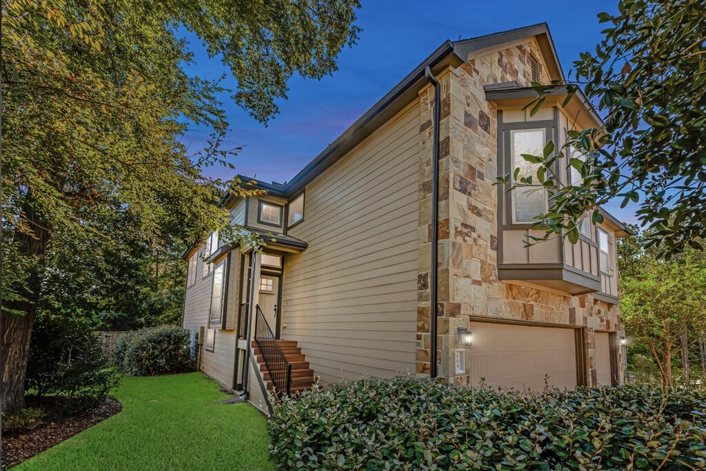 property exterior at dusk featuring a garage and a lawn