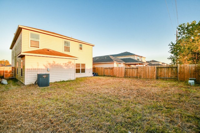 back of house featuring a fenced backyard, a lawn, and central AC unit