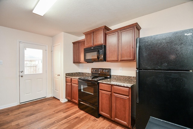 kitchen with baseboards, black appliances, brown cabinetry, and light wood-style floors