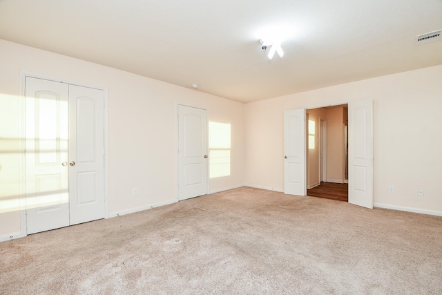 unfurnished room with baseboards, visible vents, and light colored carpet