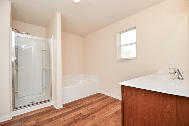 full bath featuring a stall shower, baseboards, wood finished floors, vanity, and a bath