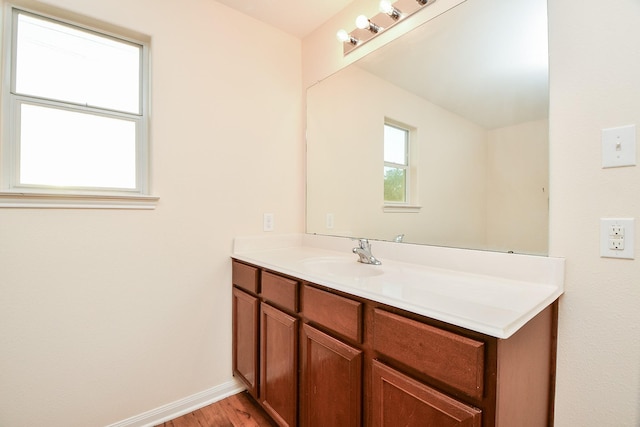 bathroom with wood finished floors, vanity, and baseboards