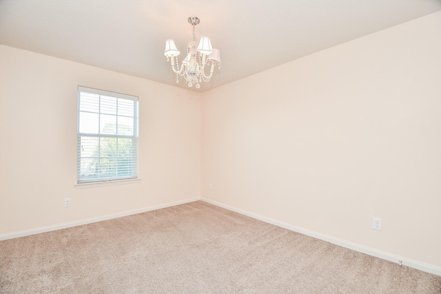 spare room with baseboards, carpet floors, and an inviting chandelier