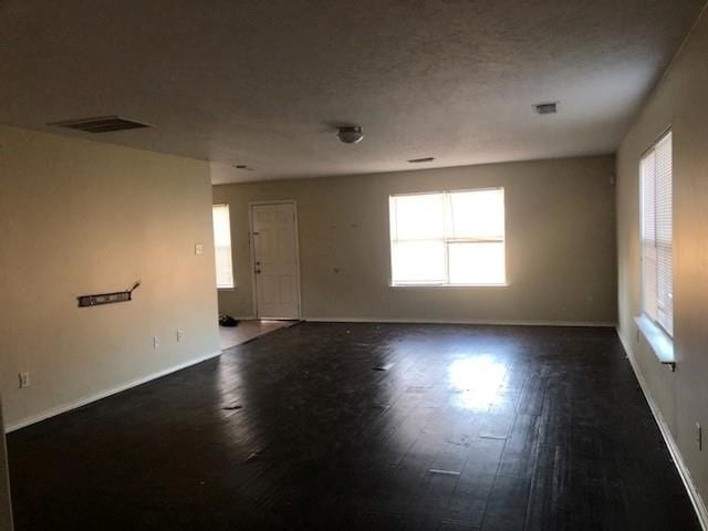 empty room featuring a textured ceiling and dark hardwood / wood-style flooring