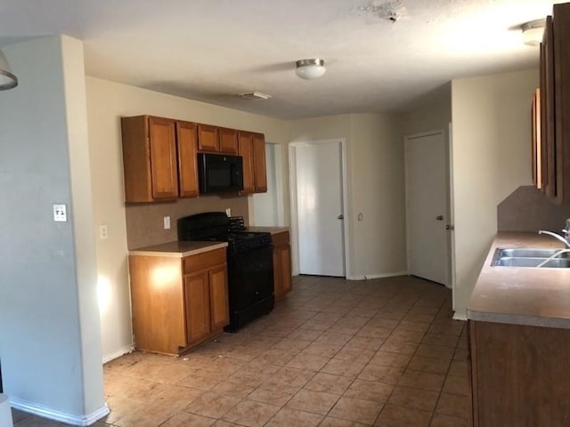 kitchen featuring sink, black appliances, and light tile patterned flooring