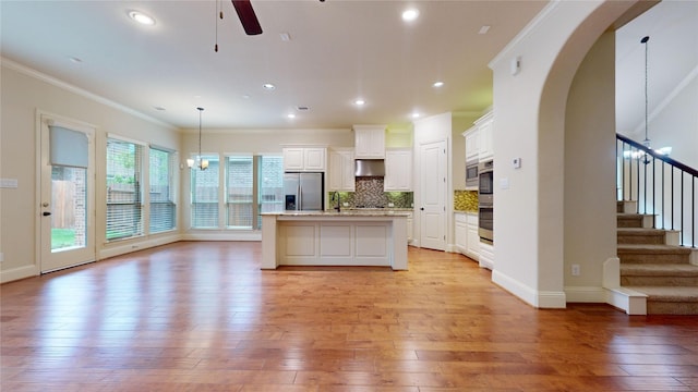 kitchen with white cabinetry, appliances with stainless steel finishes, a kitchen island with sink, and hanging light fixtures