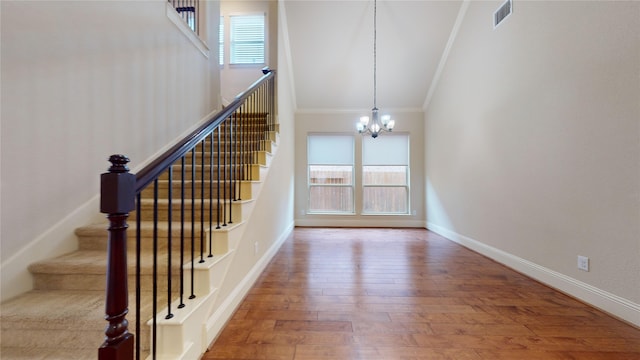 stairs with wood-type flooring, ornamental molding, a wealth of natural light, and a notable chandelier