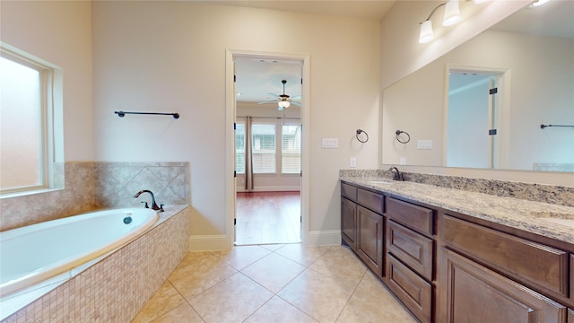 bathroom with tile patterned flooring, vanity, tiled bath, and ceiling fan