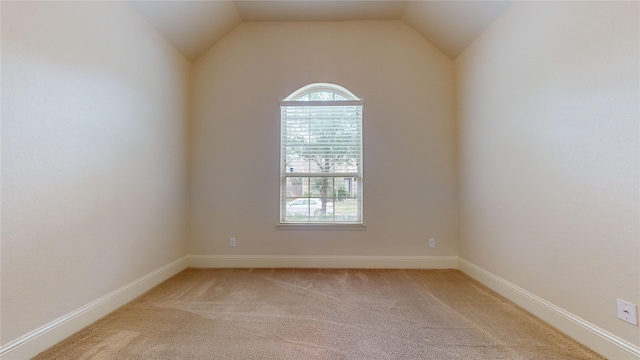 carpeted spare room with vaulted ceiling