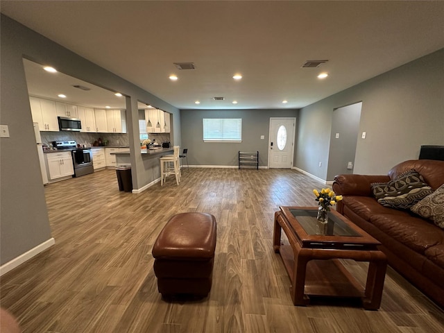 living area featuring light wood-type flooring, visible vents, baseboards, and recessed lighting