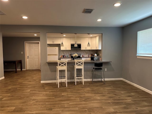 kitchen featuring a peninsula, a kitchen bar, white cabinetry, and stainless steel appliances