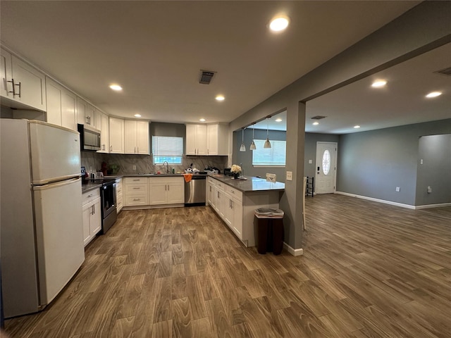 kitchen with tasteful backsplash, visible vents, white cabinets, dark countertops, and appliances with stainless steel finishes