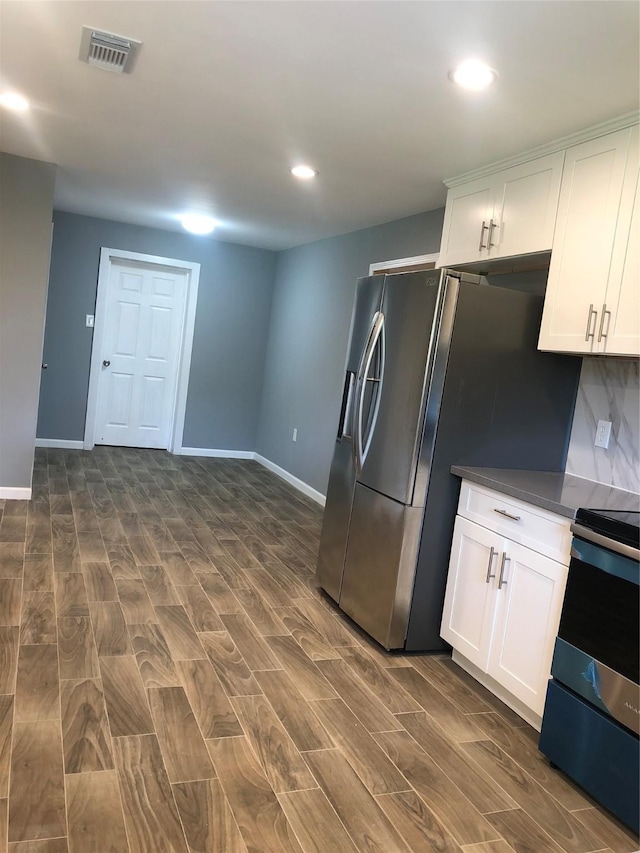 kitchen featuring stainless steel appliances, dark countertops, white cabinetry, and visible vents