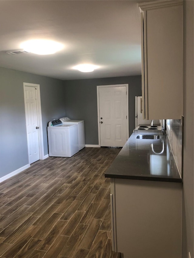 washroom featuring visible vents, dark wood-type flooring, washing machine and dryer, a sink, and laundry area