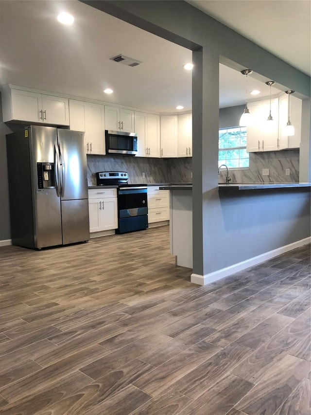 kitchen with visible vents, dark countertops, appliances with stainless steel finishes, hanging light fixtures, and white cabinetry