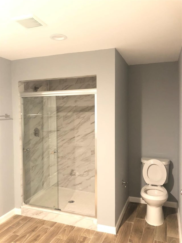 bathroom featuring a stall shower, visible vents, baseboards, toilet, and wood tiled floor