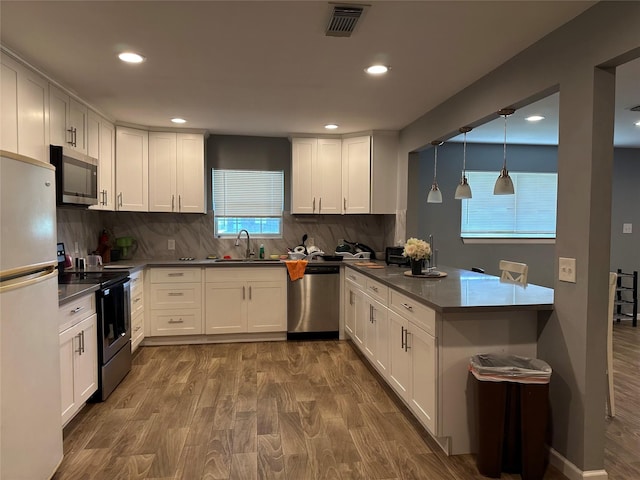 kitchen featuring stainless steel appliances, visible vents, white cabinetry, a sink, and a peninsula