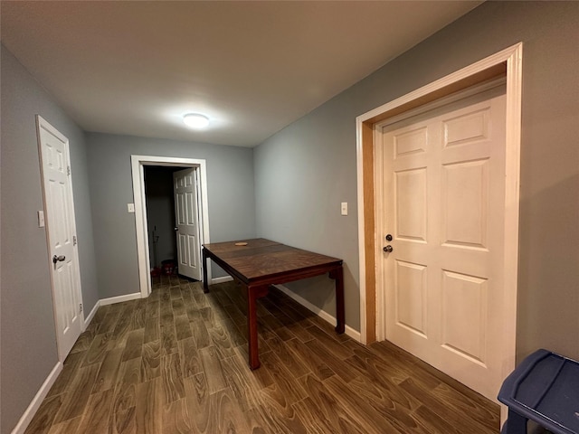 corridor with dark wood-style flooring and baseboards