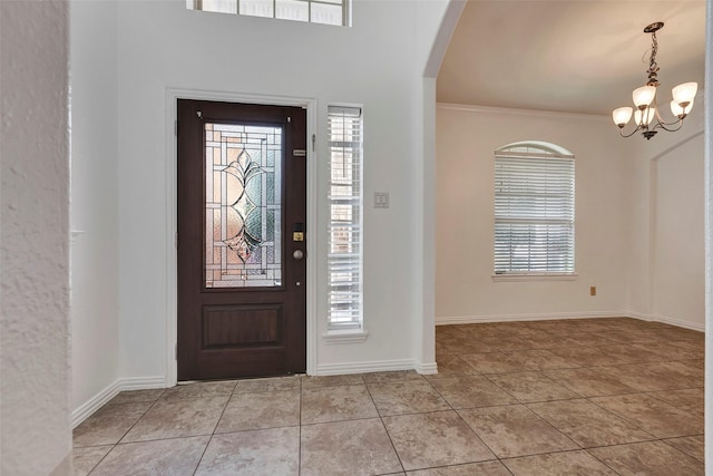 tiled foyer entrance with crown molding and a notable chandelier