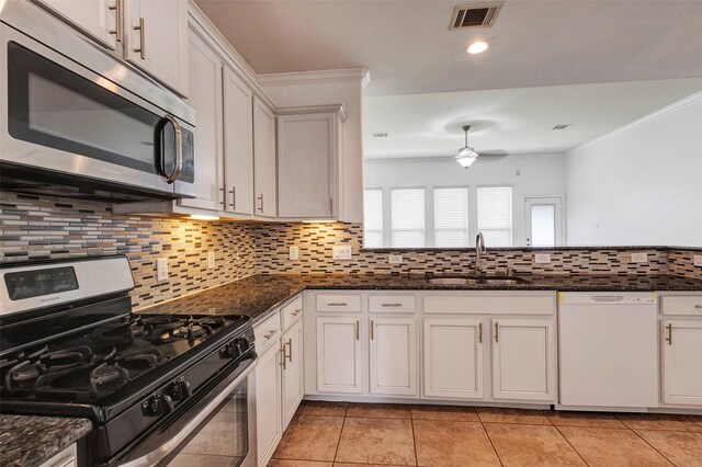 kitchen with white cabinetry, sink, dark stone countertops, decorative backsplash, and stainless steel appliances