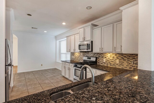 kitchen featuring sink, backsplash, stainless steel appliances, white cabinets, and light tile patterned flooring