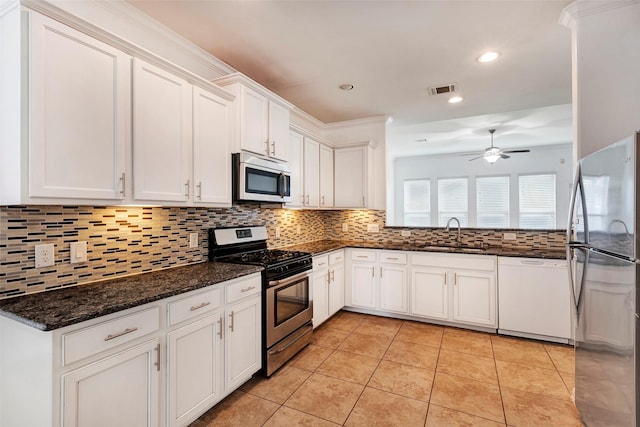 kitchen with sink, appliances with stainless steel finishes, white cabinetry, light tile patterned flooring, and dark stone counters