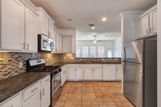 kitchen featuring appliances with stainless steel finishes, tasteful backsplash, white cabinets, dark stone counters, and light tile patterned floors