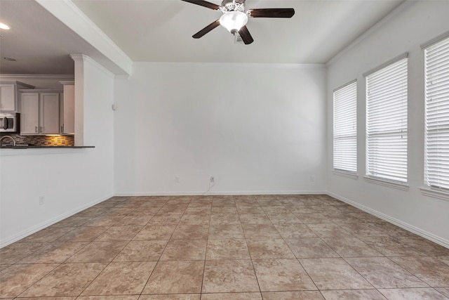 spare room with ceiling fan, ornamental molding, and light tile patterned floors