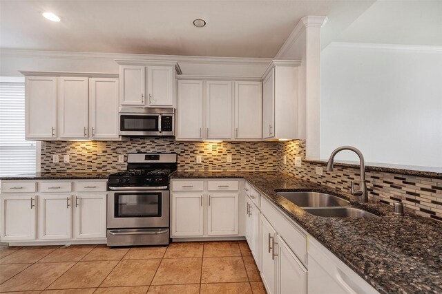 kitchen with stainless steel appliances, sink, dark stone counters, and white cabinets