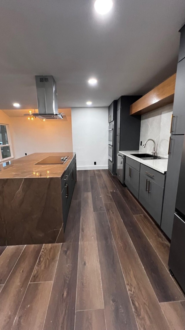 kitchen featuring dark wood-type flooring, appliances with stainless steel finishes, island range hood, and sink