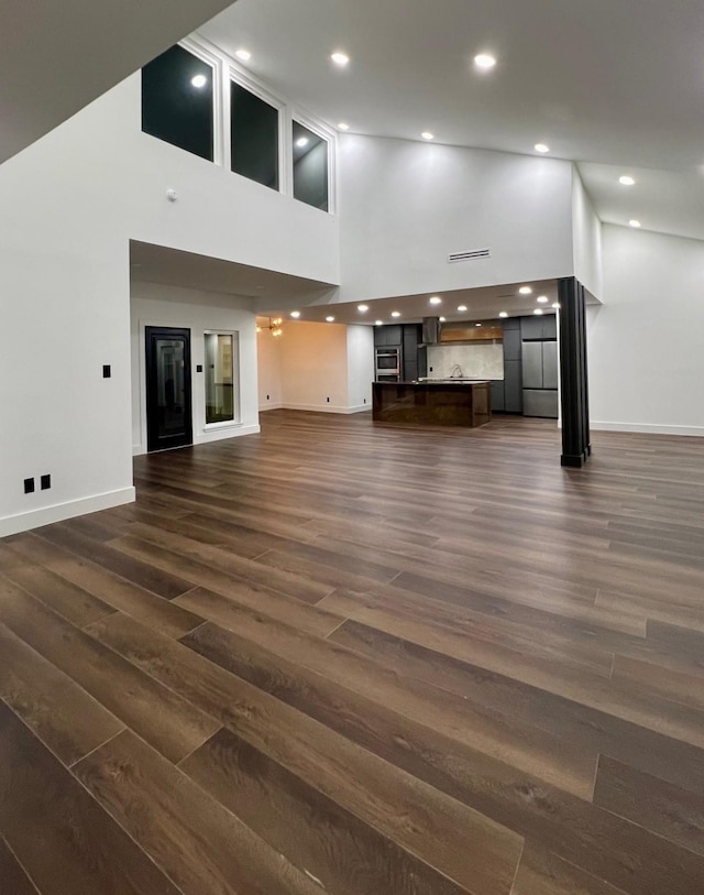 unfurnished living room featuring dark hardwood / wood-style flooring and a high ceiling