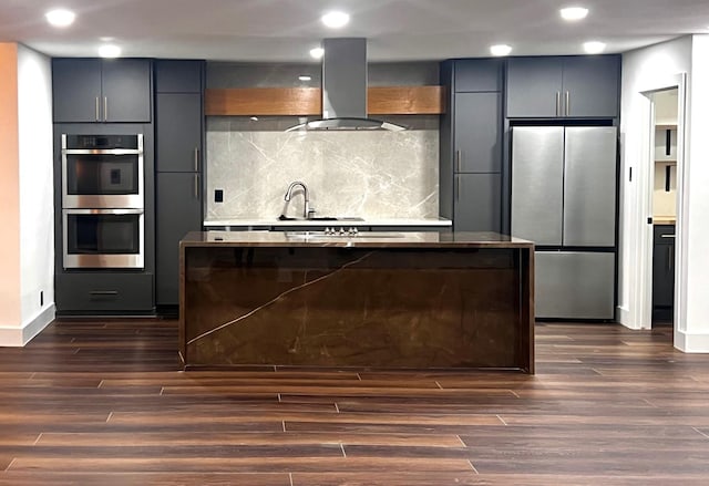 kitchen featuring dark hardwood / wood-style floors, sink, backsplash, island exhaust hood, and stainless steel appliances