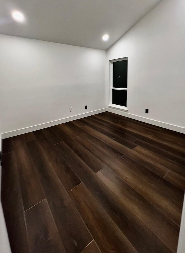 empty room featuring dark hardwood / wood-style floors and vaulted ceiling